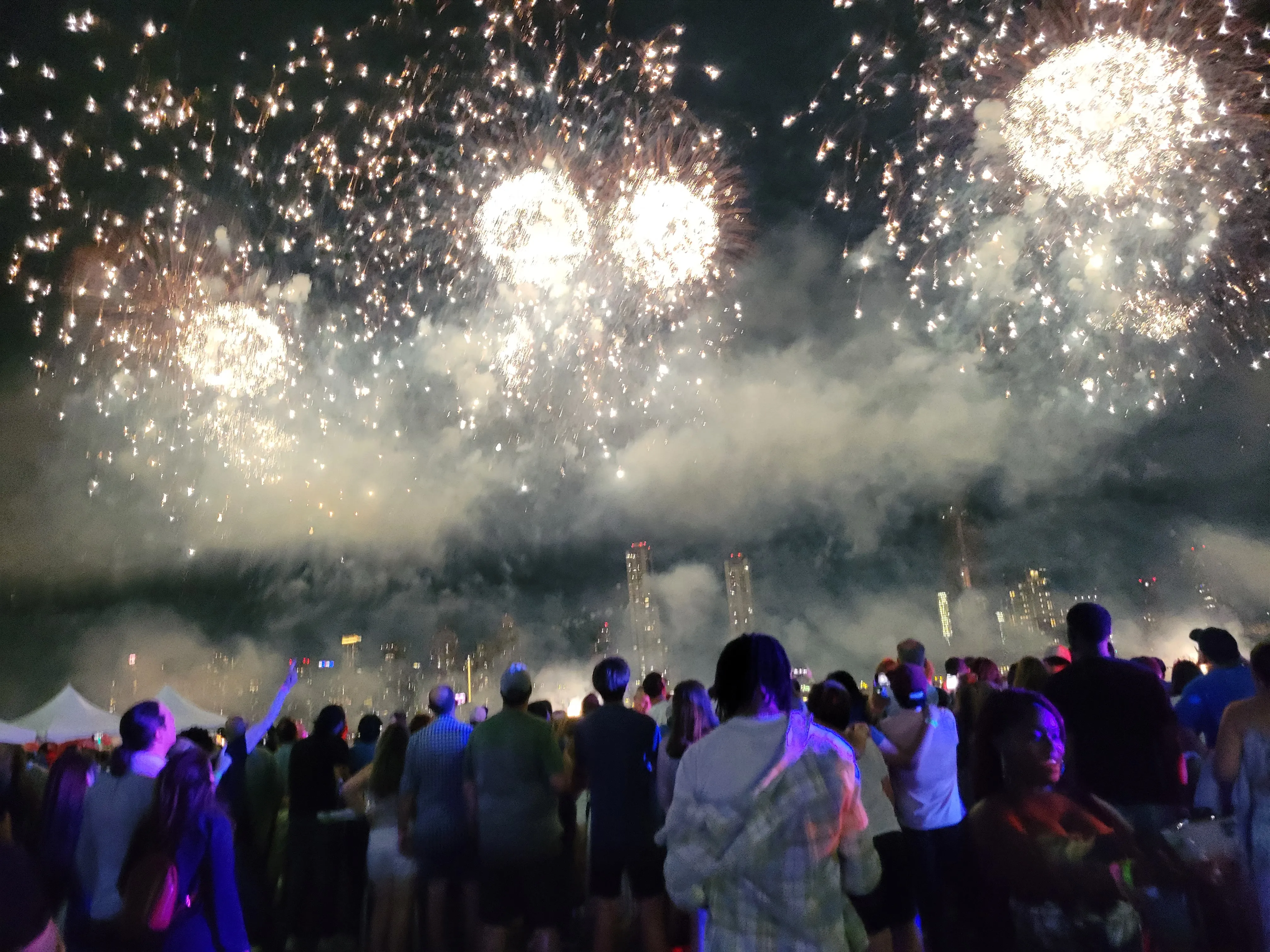 Massive fireworks bursts overhead with crowd and Manhattan skyline
