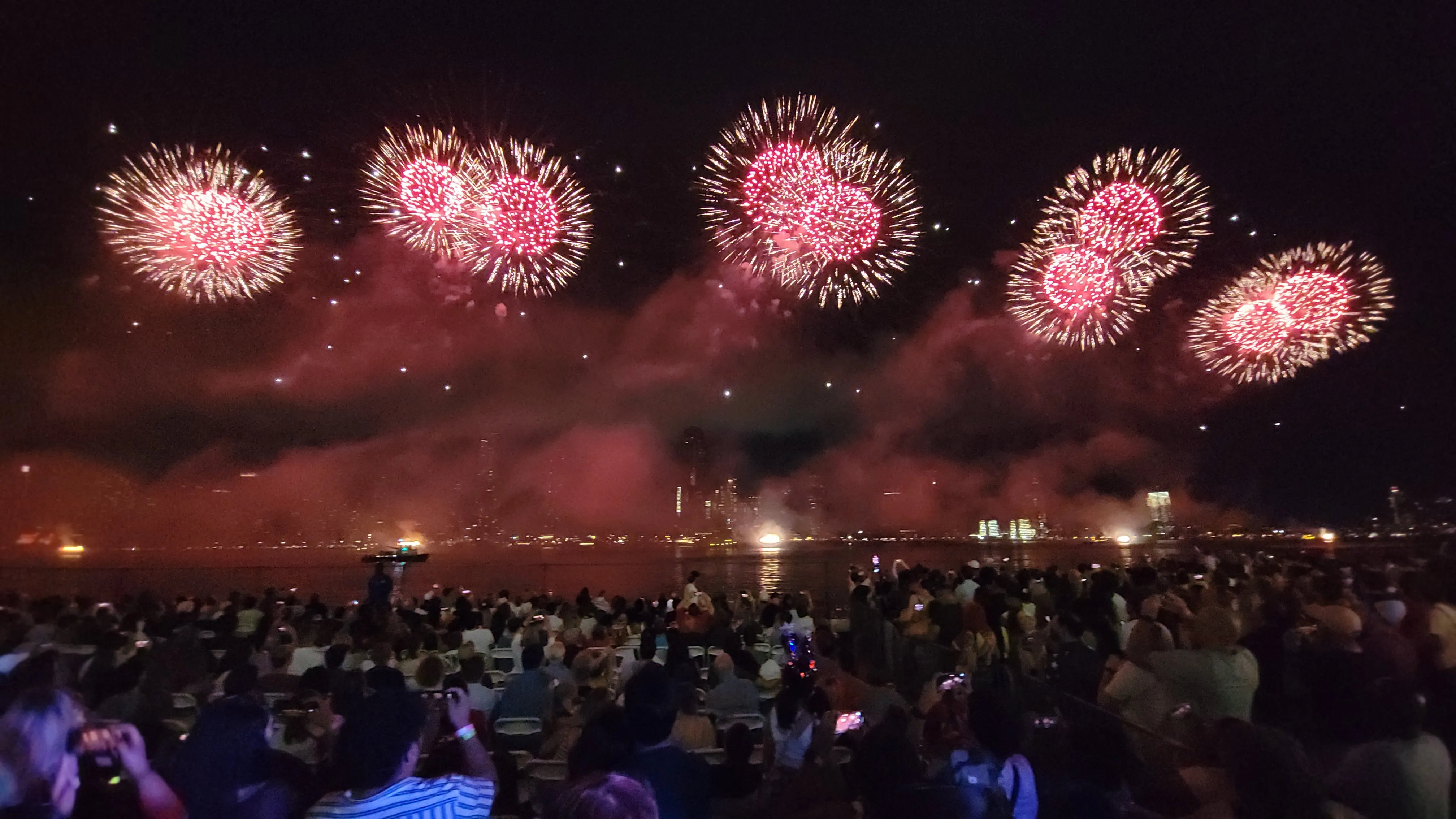 Red and pink fireworks line across the sky over East River