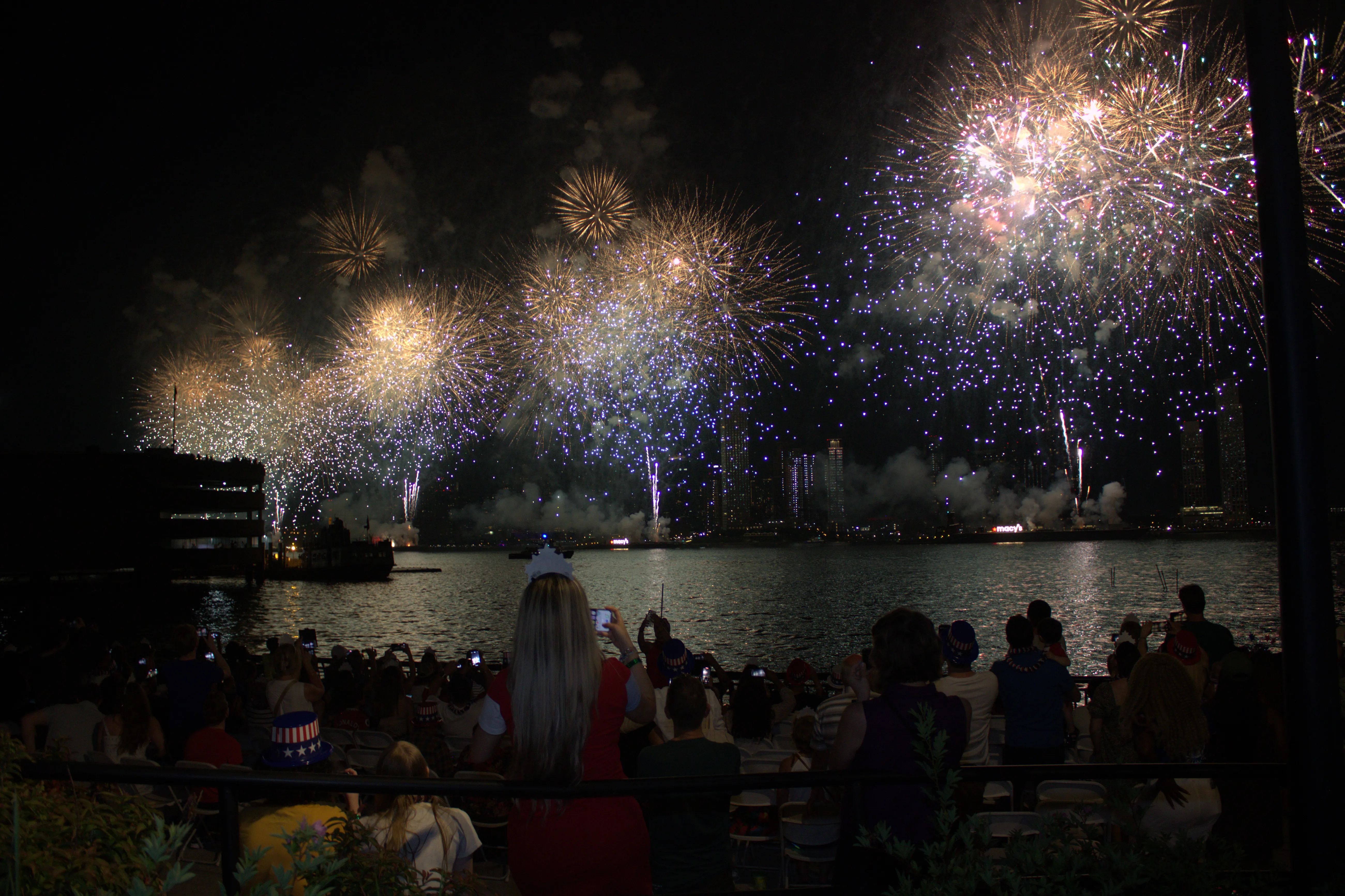 Golden fireworks over East River with waterfront crowd seating